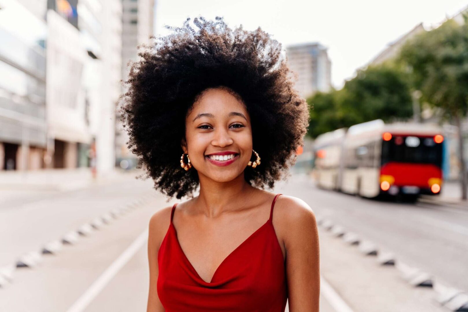 A woman in red dress standing on the side of road.