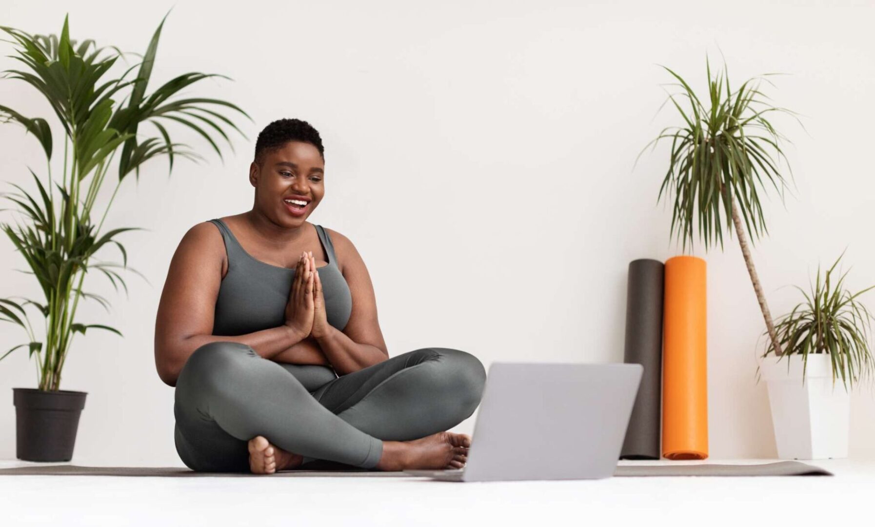 A woman sitting on the ground in front of a laptop.