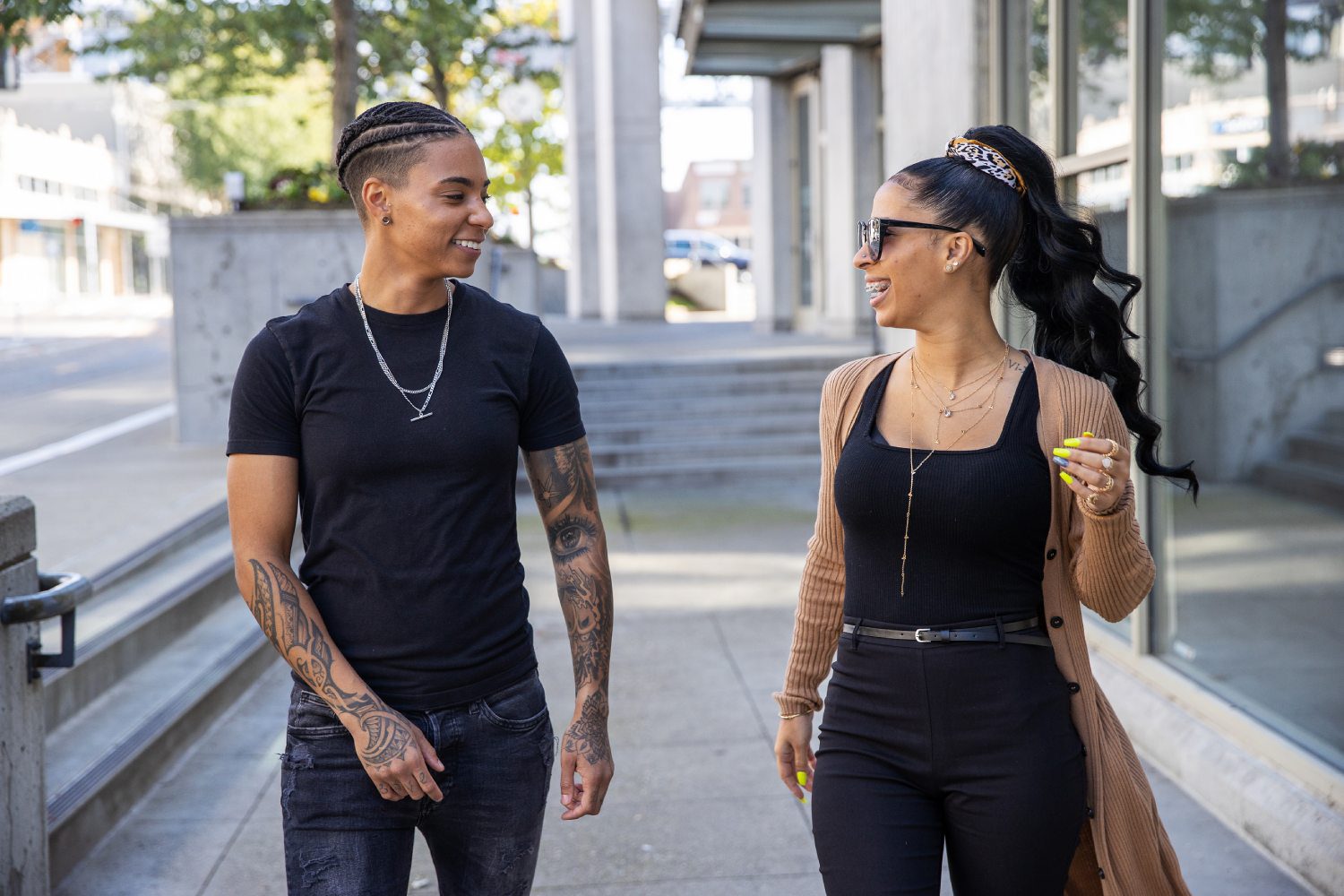 A man and woman are talking on the sidewalk.