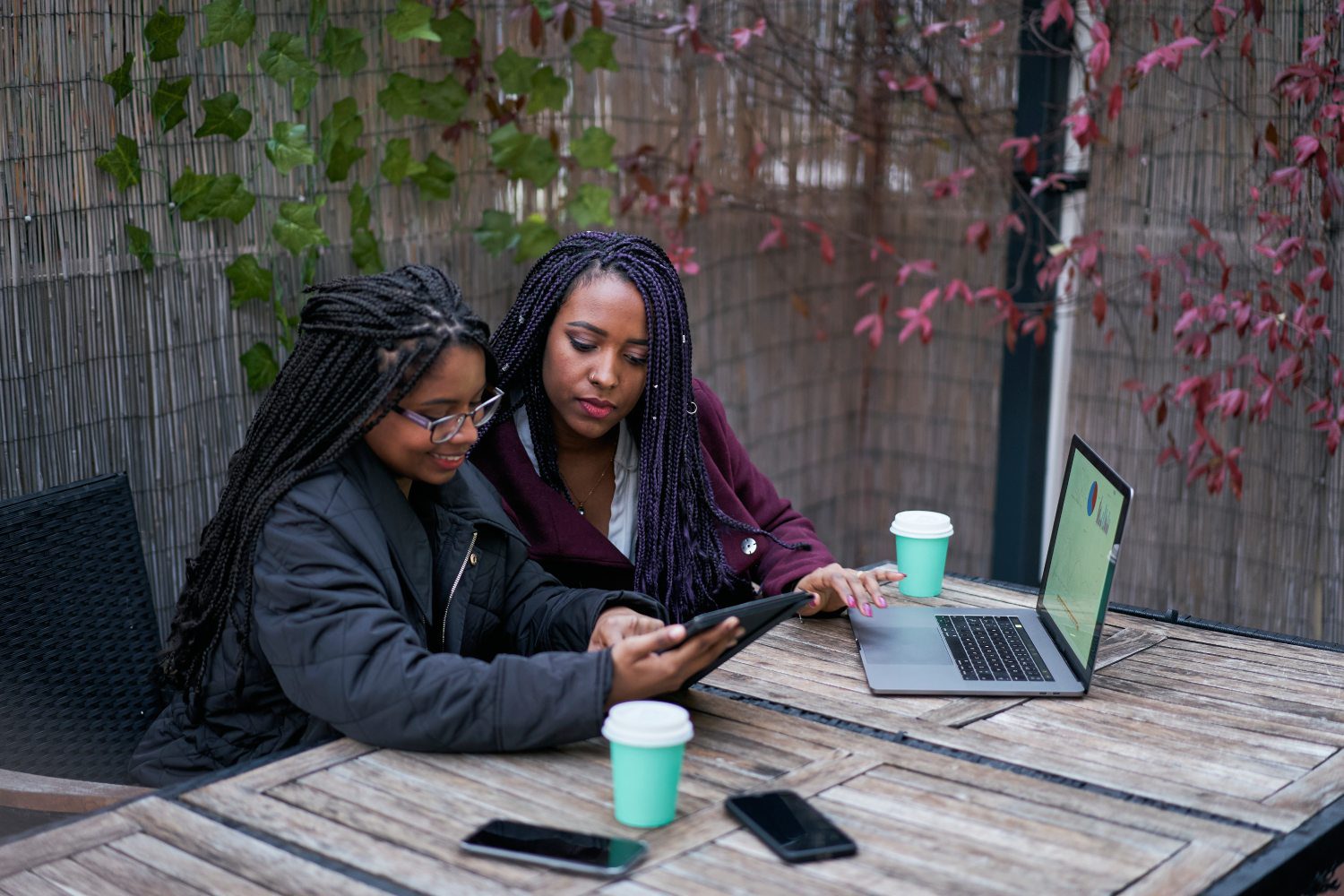 Two women sitting at a table with laptops.