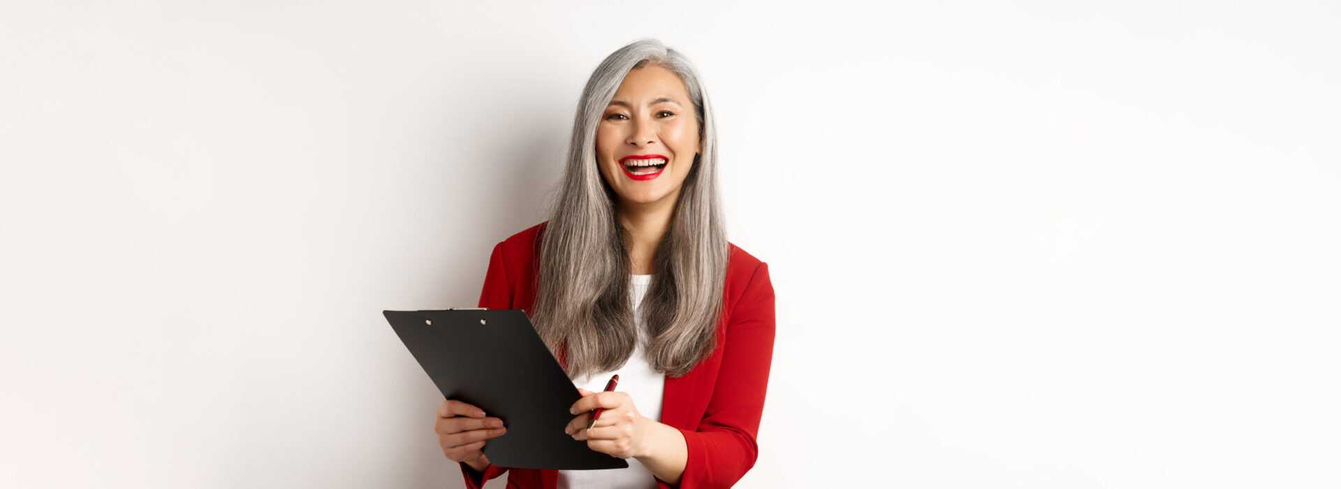 A woman with long grey hair holding a clipboard.