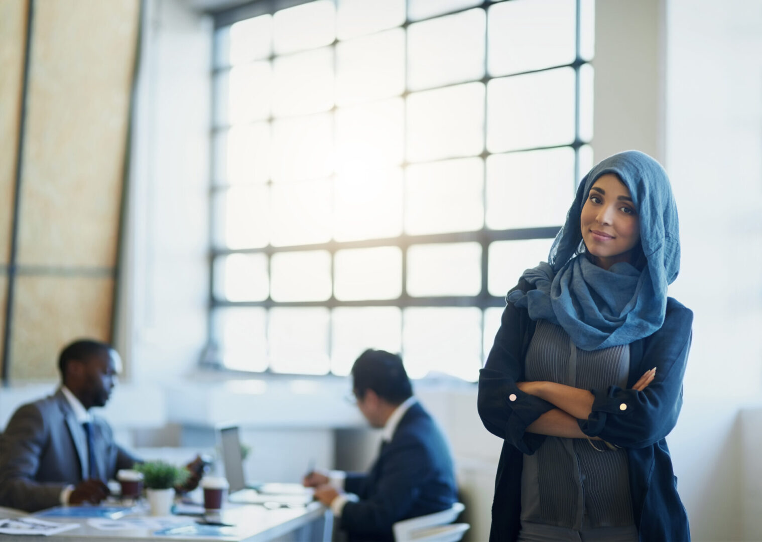 A woman in a hijab standing next to two other people.